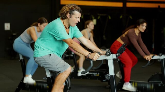 Adult man is actively engaged in an exercise bike, he does a circuit training in the Crossfit gym. Man prepares for a marathon and does cardio exercises. High quality 4k footage