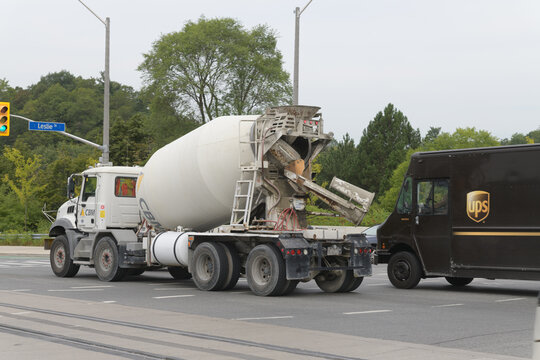 CBM (Canadian Building Materials) concrete mixer truck and UPS (United Parcel Service) delivery vehicle heading west on Eglinton Av E at Leslie St, Toronto