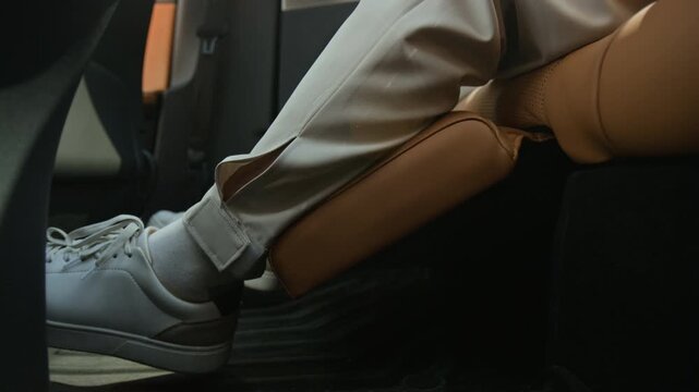 Cropped shot of unrecognizable passenger leg resting on luxury car seat leg support slowly extending upward. Footage is ideal for automotive marketing and electric vehicle comfort feature promotions