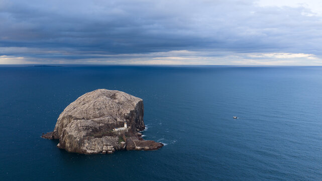 Aerial view of Bass Rock, a volcanic plug island in the Firth of Forth featuring a lighthouse and rocky cliffs surrounded by the deep blue sea in Scotland, United Kingdom.