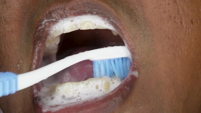 Close up of Indian young man teeth with toothbrush for dental hygiene, cleaning or oral care at home. Daily Oral Hygiene and Dental Care routine concept.