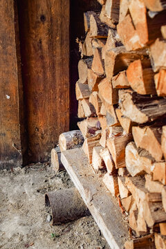 Stacked firewood beside an old wooden wall in a rustic countryside setting