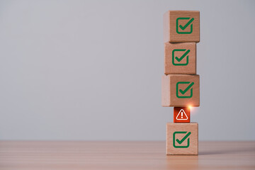 Naklejka premium Risk management concept with warning symbol interrupting green check marks on stacked wooden blocks for compliance issues, quality control, audit, assessment and business problem detection.