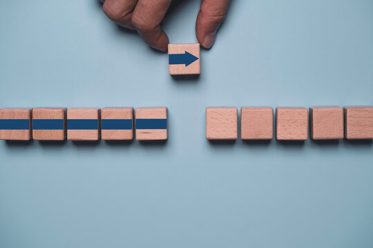 Business strategy concept with hand moving an arrow wooden block across a gap symbolizing direction, transition, problem solving, change management, decision making and overcoming obstacles.
