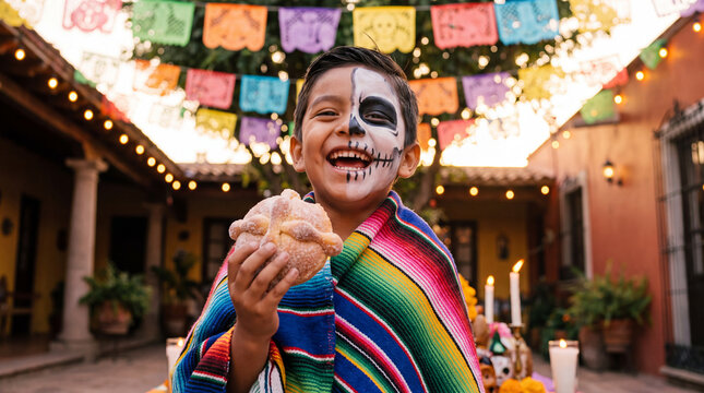Mestizo boy with half-skull calavera makeup and colorful serape laughing while holding pan de muerto, great for Day of the Dead advertising and editorial content.