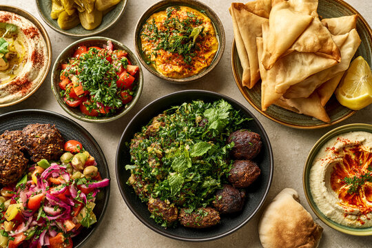 Assorted middle eastern mezze dishes including hummus falafel and salads with pita bread