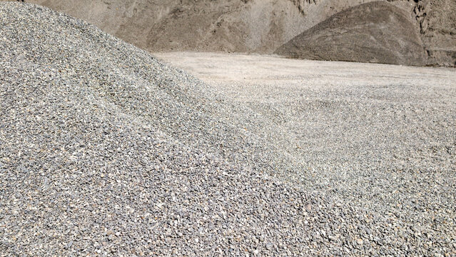 Gravel pile and scattered stones showing a close up texture of crushed rock used as aggregate in civil engineering, roadworks, and landscaping projects