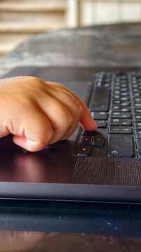 Toddler hand pressing laptop keys, close up on early digital learning and typing skills development, symbolizing childhood tech literacy and connected future preparation