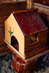 Homemade wooden birdhouse or small animal shelter with a burgundy roof in a rural backyard © Vasilisa Dorofeeva