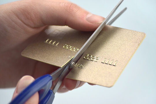 The woman is cutting her credit card in half because it expired