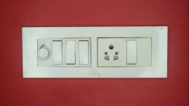 Close up of woman finger turn off or on the light to saving electrical energy. Finger pushing light switch turn on or off. White switch on red background.