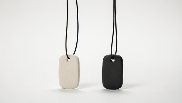 Two rectangular pendant tags in matte white and matte black hanging from thin black cords on a light background, isolated on a, transparent background
