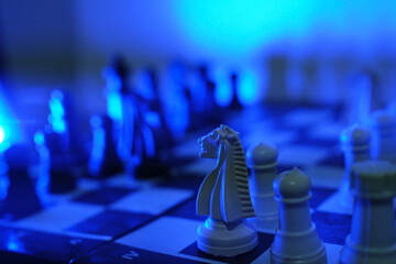 Close-up of a chess piece on a chessboard in dim blue light. World Chess Day. International Chess Day. July 20.  © PANCASONA CREATION