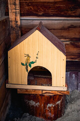 Homemade wooden bird shelter with an arched entrance, decorative bird painting and brown gabled roof © Vasilisa Dorofeeva