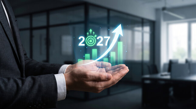 Businessman holding virtual 2027 growth chart with upward arrow and financial target