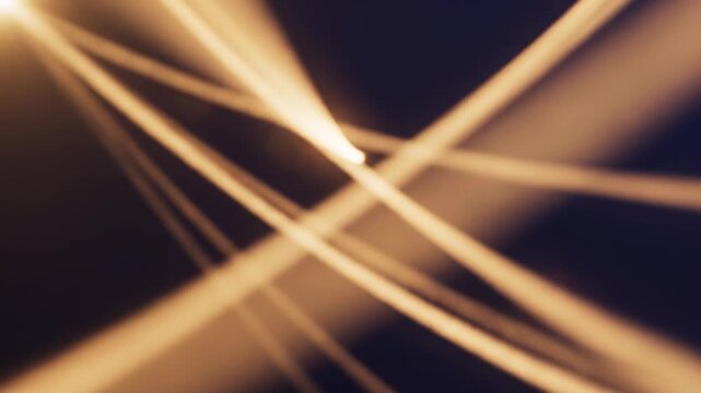 Golden light beams converging and diverging in dark space during abstract motion with lens flares