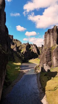 Aerial video of Fja&eth;r&aacute;rglj&uacute;fur canyon in Iceland, showcasing a winding river, steep canyon walls, lush green vegetation and dramatic volcanic landscapes from above, 4k.