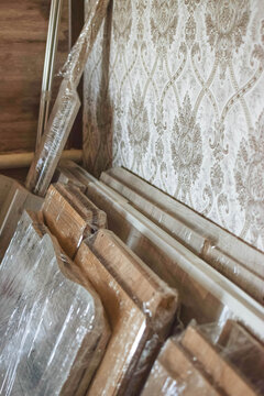 Disassembled furniture panels wrapped in transparent stretch film indoors, illustrating moving preparation, furniture storage, renovation and protective packaging