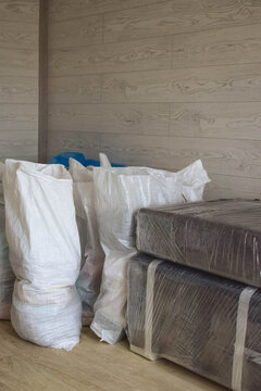 Packed belongings and furniture wrapped in stretch film inside a room, illustrating moving preparation, storage, transportation and home renovation