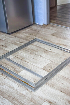 Hidden floor hatch with recessed metal handle and aluminum frame integrated into wood-pattern flooring, illustrating DIY renovation, basement access and concealed home solutions