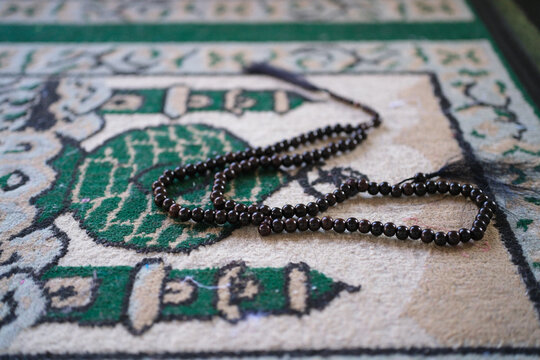 Close-up of prayer beads on a prayer mat. A background concept for Ramadan, Eid al-Fitr, or other Islamic holidays.
