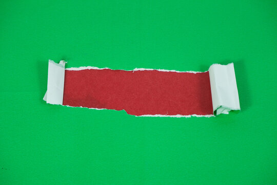 A layer of red paper revealed beneath a torn sheet of green paper. The torn green paper exposes a red background, creating a space for text.
