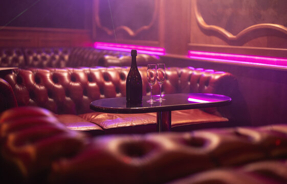 Champagne bottle on table in stylish neon bar.