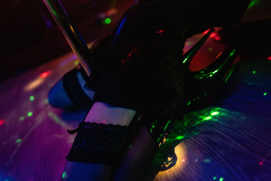 Female pole dancer legs on club stage.