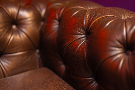 Close-up of luxury brown tufted leather sofa upholstery.
