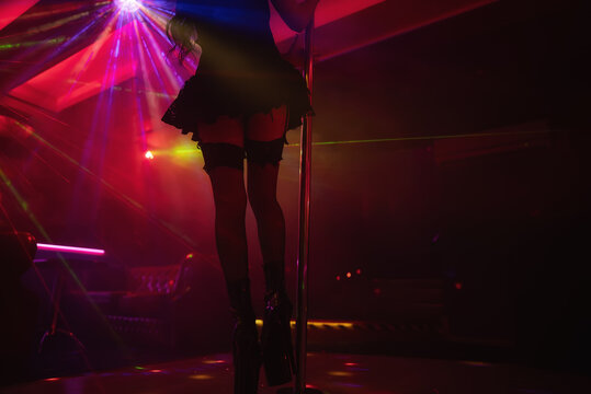 Pole dancer performing under laser lights in club.