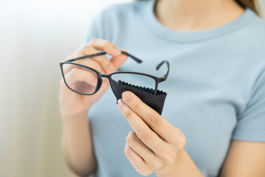 Cleaning glasses concept, close up hand of asian young woman hand holding frame of glass, use cloth wipe the lens, rub to clean eyewear for sanitary with wipe remove dust and disinfect at spectacle.