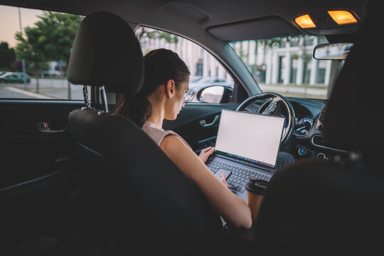 Businesswoman working on laptop in parked car