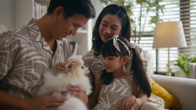 Happy Asian family playfully carry and bond with their daughter while laughing together on the sofa.creating joyful moments and family enjoying quality time at home
