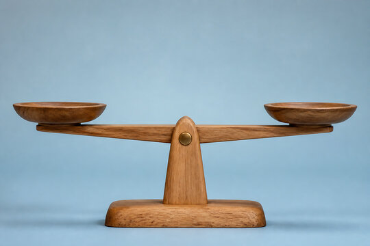 A wooden balance scale rests on a light blue surface against a plain background.