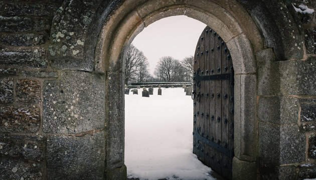 Stone Church Doorway Framing Snowy Churchyard