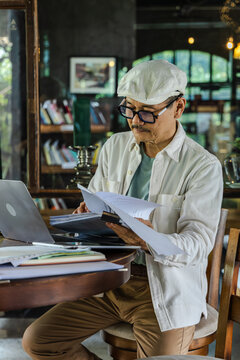 Senior small business owner works alone on laptop in cafe environment, managing financial control, planning workflow, digital tasks, business operations focus, professional mindset, elderly pensioner