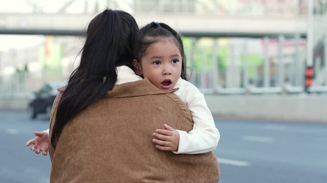 mother embracing daughter outdoors on the city street
