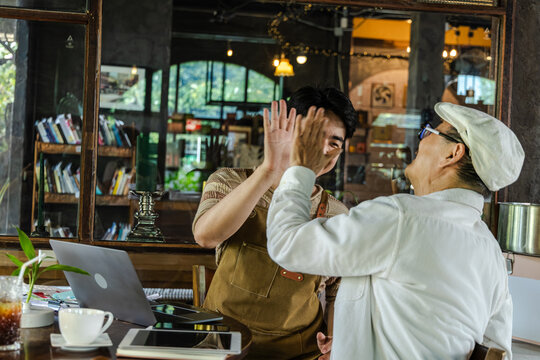 Modern small business digital technology, father and son cafe owner, young entrepreneur management, using laptop and tablet planning orders finance workflow efficiency technology business operation