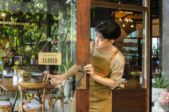 Cafe owner adjusting closed sign while looking through glass window, small business routine showing responsibility and daily management, lifestyle of entrepreneur balancing service and rest time.