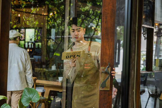 family small business coaching, senior cafe owner giving instruction to young son barista standing at storefront, learning by doing with new generation, leadership daily operation guidance concept.