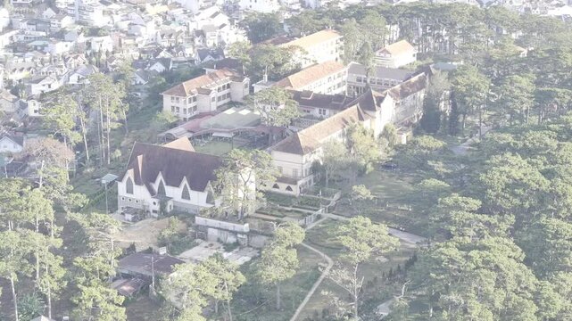 Aerial drone view of Lam Dong Ethnic Minority Boarding School in Cam Ly Ward, Da Lat, Vietnam, surrounded by pine forests and the scenic highlands of Lam Dong Province.