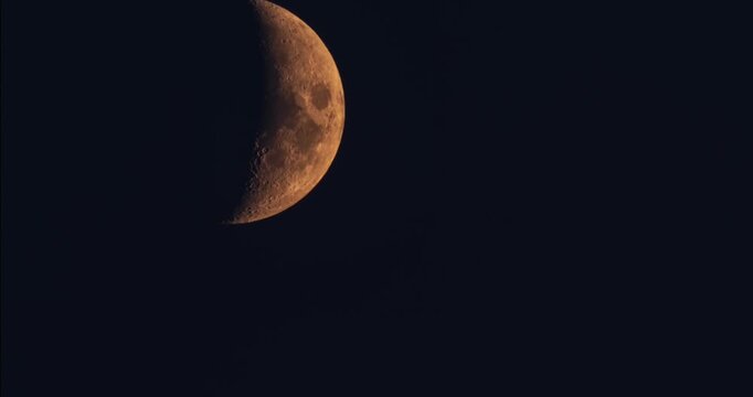 Night sky time lapse with clear orange half moon moving in space