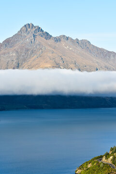 Mountain rising above low cloud and lake near Queenstown, New Zealand