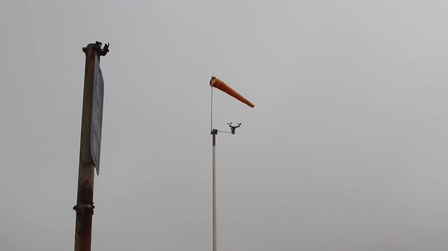 Orange Windsock And Cup Anemometer Overcast Sky With Sign Post And Pole

