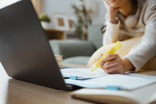 Debt worry is shown by a woman leaning over bills at a laptop, expressing financial stress, household budget difficulty, and unmanaged expenses. Highlight important, education; highlight focus.