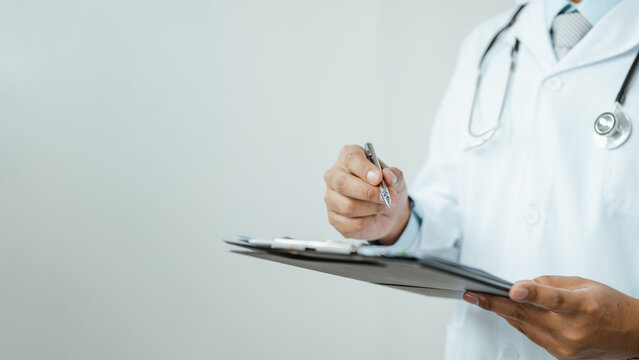 Healthcare professional writes on a clipboard while wearing a stethoscope, showing medical insurance records, doctor service, and patient cost. Medical insurance, paperwork; medical focus.
