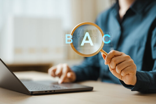 Business professional uses a magnifier near a laptop and letter blocks, depicting financial analysis, careful data inspection, and research report work. Price comparison, products; price focus.