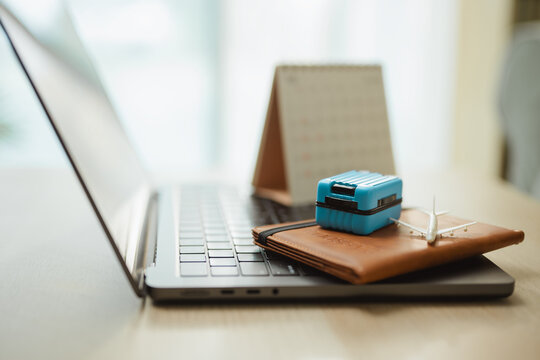 Travel budget concept displays luggage and an airplane on a wallet by a laptop, highlighting savings goals and vacation preparation for commercial use. Travel planning, suitcase; travel focus.
