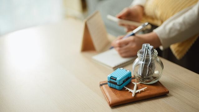 Travel budget still life combines luggage, an airplane, and a money jar, illustrating savings discipline and future journey preparation for commercial use. Travel savings, vacation; travel focus.
