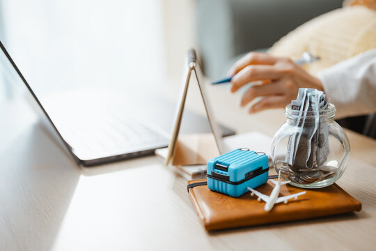 Travel budget workspace combines a laptop, luggage, airplane, and coin jar, representing savings strategy and practical vacation planning. Travel traveling, traveler; travel focus.